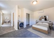 Thumbnail 2 of 13 - A bedroom with a large bed and a washing machine in the corner.