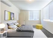 Thumbnail 5 of 13 - A bedroom with a bed, a yellow stool, and two framed pictures on the wall.