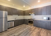 Thumbnail 6 of 13 - A modern kitchen with wooden cabinets and stainless steel appliances.
