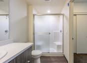 Thumbnail 8 of 13 - A white bathroom with a toilet, sink, and walk-in shower.