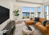Thumbnail 1 of 23 - a living room with a leather couch and a television and a view of the water at Liza Apartments, Seattle, Washington, 98102