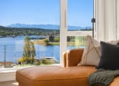Thumbnail 6 of 23 - a living room with a couch and a window overlooking a lake and mountains at Liza Apartments, Seattle, Washington