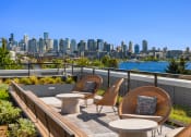 Thumbnail 11 of 23 - a rooftop deck with chairs and tables with a view of the city at Liza Apartments, Seattle, 98102