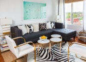Thumbnail 1 of 15 - a living room with a black couch and tables