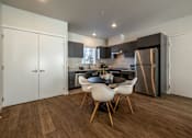 Thumbnail 1 of 6 - A modern kitchen with a dining table and chairs.