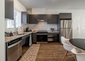 Thumbnail 2 of 6 - A modern kitchen with a black countertop and stainless steel appliances.