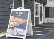 Thumbnail 9 of 10 - the rivet leasing office sign in front of a building