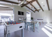 Thumbnail 16 of 30 - a recreation room with a foosball table and a table with chairs and a