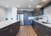 Thumbnail 1 of 30 - a modern kitchen with dark cabinets and white countertops and a stainless steel refrigerator