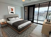 Thumbnail 3 of 22 - A bedroom with a bed, nightstand, and a ceiling fan.