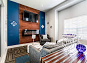 Thumbnail 5 of 16 - A modern living room with a grey couch and a wooden wall.