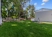 Thumbnail 32 of 34 - a backyard with a white house and a tree