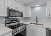 Thumbnail 4 of 34 - a kitchen with white cabinets and stainless steel appliances