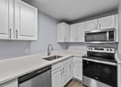 Thumbnail 3 of 34 - a kitchen with white cabinets and black and white appliances