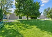 Thumbnail 30 of 34 - a park with green grass and trees and buildings in the background