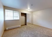 Thumbnail 17 of 25 - A carpeted bedroom with a large window at Heron Hills apartments in Gresham Oregon.