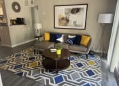 Thumbnail 7 of 26 - A living room with a grey couch, a coffee table, and a patterned rug.