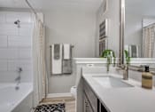 Thumbnail 6 of 24 - A bathroom with a white tub, sink, and towel rack.