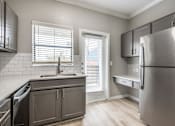 Thumbnail 15 of 24 - A kitchen with a stainless steel refrigerator and wooden floors.