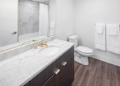 Thumbnail 13 of 35 - A bathroom with a marble countertop and a toilet.