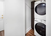 Thumbnail 19 of 35 - A white washing machine sits in a laundry room.