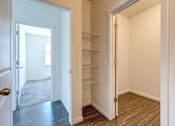 Thumbnail 7 of 24 - A hallway with a door on the left and a closet with shelves on the right.