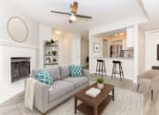 Thumbnail 1 of 7 - A living room with a grey couch, a coffee table, and a fireplace.