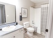 Thumbnail 4 of 7 - A bathroom with a toilet, sink, and shower.