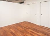 Thumbnail 6 of 29 - A room with wooden floors and white walls with two doors.