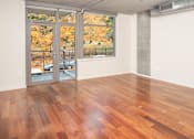 Thumbnail 4 of 29 - A room with a wood floor and a view of trees outside through a glass door.