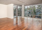 Thumbnail 11 of 29 - A room with wooden floors and a balcony with a view of houses.