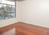 Thumbnail 9 of 29 - Empty room with wooden flooring and a window.