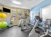 Thumbnail 4 of 18 - a gym with exercise machines and a yellow and blue wall