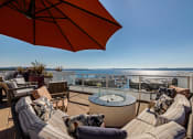 Thumbnail 25 of 26 - Vela Apartments  seating area with a fire pit and a view of the water