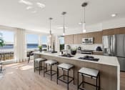 Thumbnail 1 of 26 - Vela Apartments kitchen with a large island with stools and a large window with a view of Lake Washington