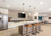 Thumbnail 13 of 23 - A modern kitchen with a bar area and a refrigerator.