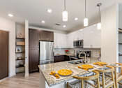 Thumbnail 1 of 23 - A kitchen with a marble countertop and wooden chairs.