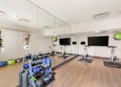 Thumbnail 18 of 23 - A gym with a mirrored wall and exercise equipment.