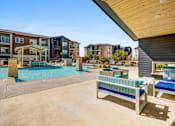 Thumbnail 18 of 20 - A pool area with a bench and a table in front of apartment buildings.