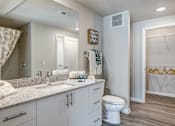 Thumbnail 5 of 20 - A bathroom with a white toilet, sink, and a mirror.