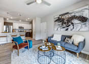 Thumbnail 2 of 20 - A living room with a blue couch and a large painting on the wall.