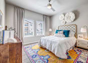 Thumbnail 4 of 20 - A bedroom with a white bed and a ceiling fan.