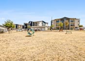 Thumbnail 19 of 20 - A playground with a green ring and a bench in front of apartment buildings.