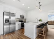 Thumbnail 5 of 12 - a white kitchen with a island and stainless steel refrigerator