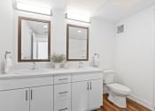 Thumbnail 9 of 12 - a white bathroom with two mirrors and a toilet
