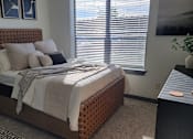 Thumbnail 4 of 27 - A bedroom with a bed, nightstand, and window with blinds at Urban Square, Denton, Texas