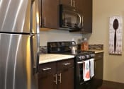 Thumbnail 7 of 27 - a kitchen with stainless steel appliances and wooden cabinets at Urban Square, Denton, TX