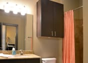 Thumbnail 11 of 27 - a bathroom with an orange shower curtain and a toilet and sink at Urban Square, Denton, TX, 76210