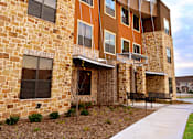 Thumbnail 26 of 27 - an exterior view of a building with a bench in front of it at Urban Square, Denton, TX