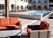 Thumbnail 15 of 27 - an outdoor lounge area with chairs and a pool at an apartment complex at Urban Square, Denton, TX, 76210